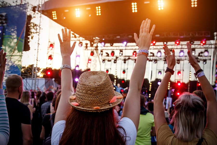 Excited teenagers at a music festival, hands in the air, soaking up the energy and fun of the concert