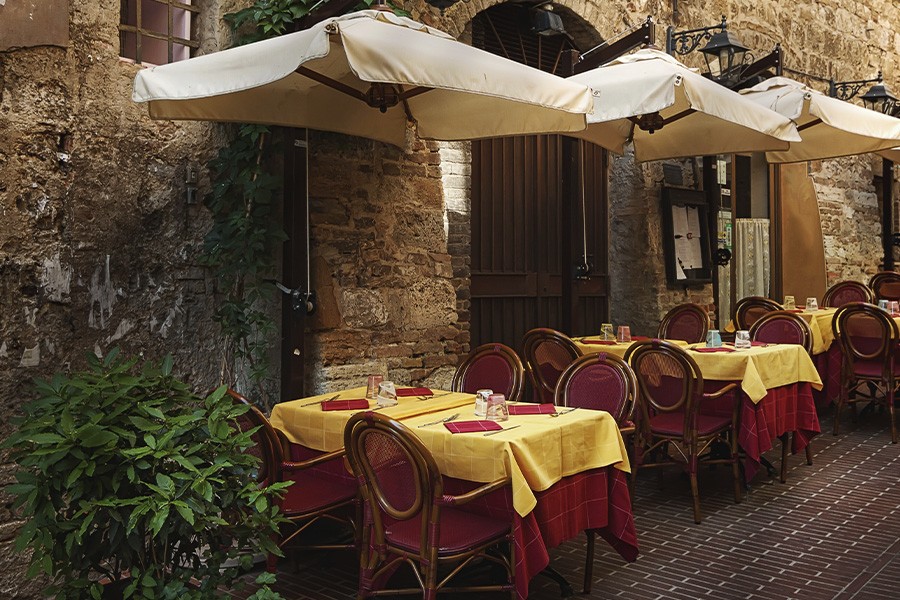 A charming restaurant with tables and chairs set in a brick alley, capturing the festive atmosphere of Siena, Italy.
