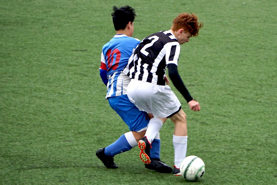 Two soccer players on a field during the Siena FC Summer Camp, engaged in practice and teamwork